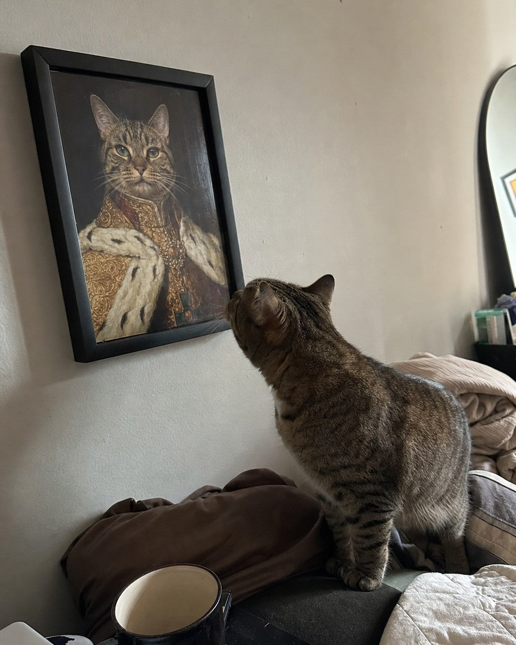 A cat inspecting its own framed renaissance portrait at home